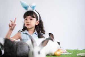 sonriente pequeño niña y con su amado mullido conejo, exhibiendo el belleza de amistad Entre humanos y animales foto