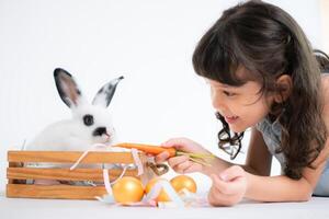 sonriente pequeño niña y con su amado mullido conejo, exhibiendo el belleza de amistad Entre humanos y animales foto