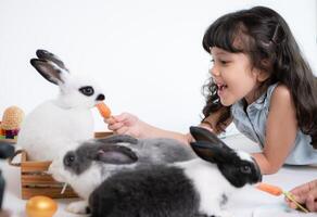 sonriente pequeño niña y con su amado mullido conejo, exhibiendo el belleza de amistad Entre humanos y animales foto