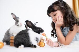 sonriente pequeño niña y con su amado mullido conejo, exhibiendo el belleza de amistad Entre humanos y animales foto