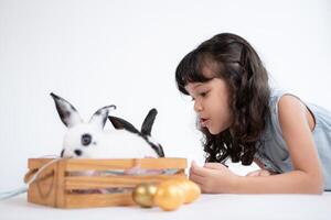 sonriente pequeño niña y con su amado mullido conejo, exhibiendo el belleza de amistad Entre humanos y animales foto