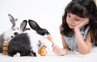 sonriente pequeño niña y con su amado mullido conejo, exhibiendo el belleza de amistad Entre humanos y animales foto