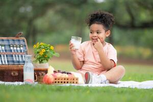 Happy family enjoying a picnic in the park, with kids drinking  milk, surrounded by nature photo