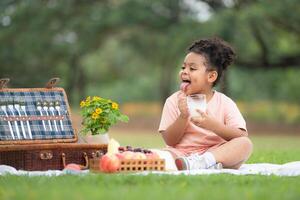 Happy family enjoying a picnic in the park, with kids drinking  milk, surrounded by nature photo