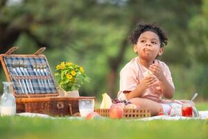 contento familia disfrutando un picnic en el parque, con niño comiendo mermelada pan, rodeado por naturaleza foto