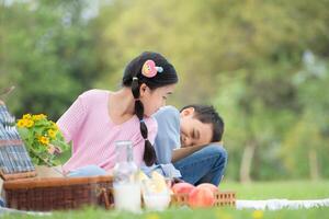 Happy family enjoying a picnic in the park, Children sitting back to back and reading books. photo