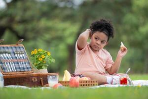 contento familia disfrutando un picnic en el parque, con niño comiendo mermelada pan, rodeado por naturaleza foto