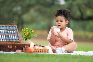 Happy family enjoying a picnic in the park, with kids drinking  milk, surrounded by nature photo