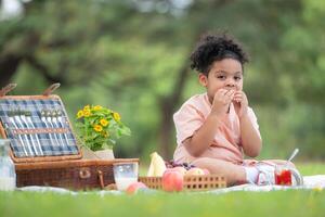 Happy family enjoying a picnic in the park, with kid eating jam bread, surrounded by nature photo