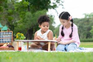 contento familia disfrutando un picnic en el parque, niños son teniendo divertido dibujo en papel metido en el mesa. foto