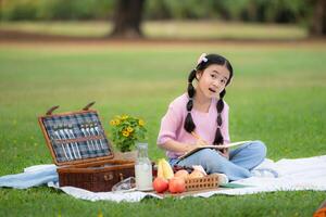 contento familia disfrutando un picnic en el parque, niña sentado y leyendo libros. foto