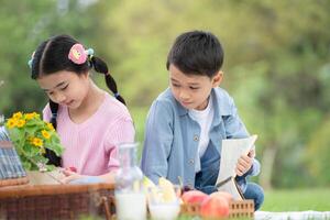 Happy family enjoying a picnic in the park, Children sitting back to back and reading books. photo