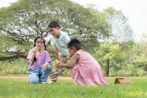 Children sitting in the park with blowing air bubble, Surrounded by greenery and nature photo