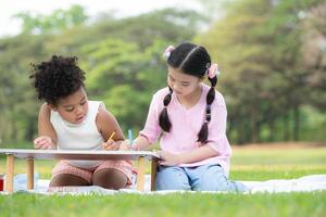 contento familia disfrutando un picnic en el parque, niños son teniendo divertido dibujo en papel metido en el mesa. foto