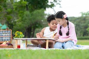 contento familia disfrutando un picnic en el parque, niños son teniendo divertido dibujo en papel metido en el mesa. foto