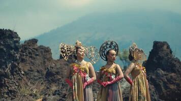 Two women in traditional costumes against a volcanic landscape. video