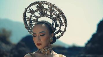 Woman in avant-garde headpiece and makeup posing in a dramatic outdoor setting. video