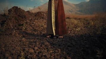 Close-up of a person's feet wearing sandals on rocky terrain with mountains in the background at dusk. video