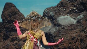 Traditional dancer in ornate costume performing with volcanic rocks in the background. video