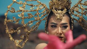 Woman with ornate golden headpiece reaching out, selective focus, vibrant colors. video