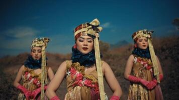 Three women in traditional attire with floral decorations posing against a blue sky. video