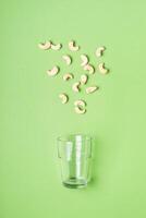 cashew nuts and glass on green background. Health care, diet and nutrition concept photo