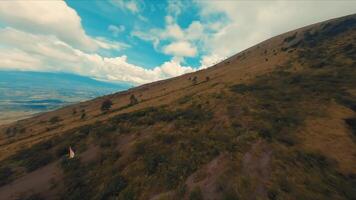 adembenemend antenne visie van een bergachtig landschap met weelderig groen en een kronkelend spoor onder een enorm blauw lucht met wolken. video