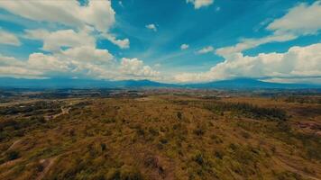 Aerial view of a vast, dry landscape with scattered vegetation under a blue sky with clouds. video