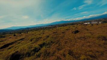 naturskön antenn se av en frodig landskap med en berg räckvidd under en blå himmel med strimmig moln. video