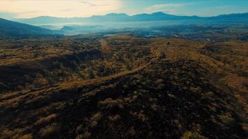 Aerial view of a rugged landscape with undulating terrain and distant mountains video