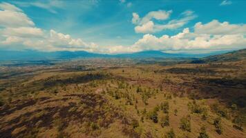 Scenic landscape with rolling hills and sparse vegetation under a vast blue sky with clouds. video