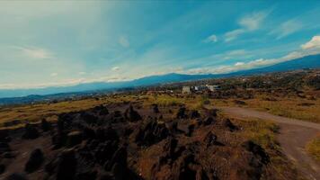 Aerial view of a rural landscape with a road leading through fields towards mountains under a blue sky video