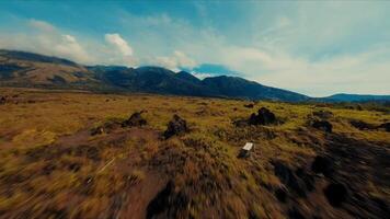 panoramisch visie van een sereen grasland met ver weg bergen onder een blauw lucht met wolken. video