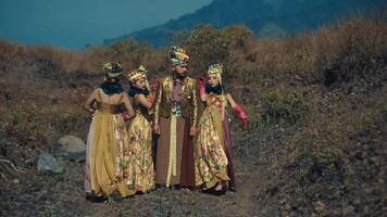 Three people in traditional Balinese attire standing on rocky terrain with mountains video