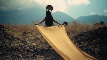 Woman holding fabric with mountains in background, concept of freedom and adventure. video