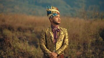 Man in traditional attire standing in a field with a serene expression, cultural fashion concept. video