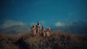 Group of people walking in a field with a mountainous backdrop. video