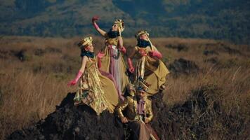 Three women in elaborate medieval costumes posing dramatically in a rugged field with mountains video