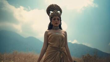 Woman in ornate headdress posing against mountainous backdrop. video