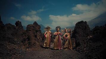 Group of women in traditional dresses walking on rocky terrain with mountain in background. video