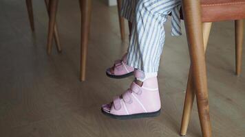 low angle view of kid feet with legs orthosis.sitting on a chair video