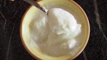 top view of spoon pick fresh yogurt in a bowl on table video