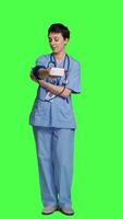 Front view Medical assistant showing tonometer used to measure arterial blood pressure, standing against greenscreen backdrop. Nurse working with sphygmomanometer tool to take measurement at checkup. Camera A. video