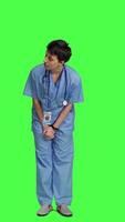 Front view Stressed nurse being in a hurry with the checkup appointments, waiting for patients to arrive at examinations. Medical assistant with scrubs acting impatient against greenscreen backdrop. Camera A. video