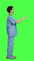 Profile Cheerful nurse giving thumbs up sign against greenscreen backdrop, showing positive gesture with a like. Medical assistant shows her approval, recommending something and being satisfied. Camera A. video