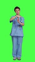 Vorderseite Aussicht medizinisch Assistent geben Auszeit Symbol gegen grüner Bildschirm Hintergrund, zeigen Grenzen und fragen zum ein Unterbrechung. Krankenschwester tun Pause oder halt Geste während sie trägt Blau Peelings. Kamera a. video
