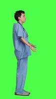 Profile Medical assistant shrugging and doing i dont know sign in studio, acting clueless and uncertain against greenscreen backdrop. Nurse in scrubs gesticulating doubtful reaction, unsure girl. Camera B. video