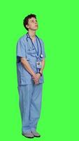 Side view Displeased nurse saying no and sighing against greenscreen backdrop, acting disappointed while she wears blue scrubs. Medical assistant with expertise shows negative gesture, being tired. Camera A. video