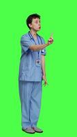 Side view Displeased irritated nurse shouting no and arguing with someone against greenscreen backdrop, showing rage and anger while she wears hospital scrubs. Aggressive medical assistant. Camera A. video