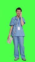 Front view Medical assistant talking to patients on landline phone call in studio, using office retro telephone with cord against greenscreen. Nurse answering hospital line to make appointments. Camera A. video